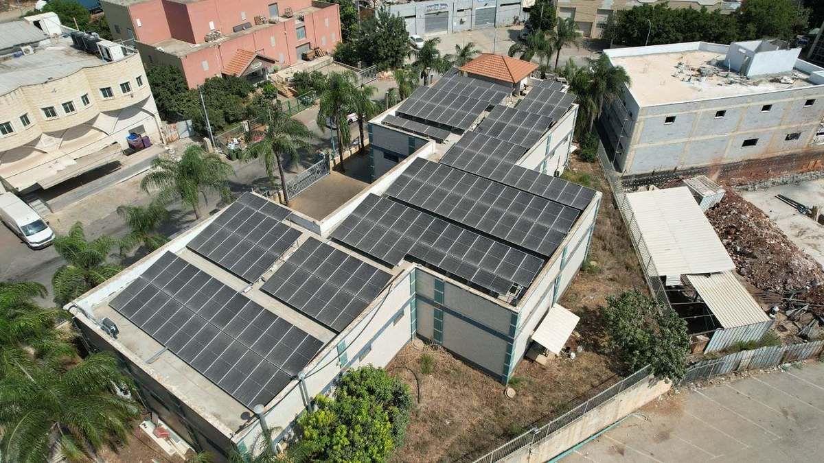 פאנלים סולאריים על גג מבנה תעשייתי בכמה מפלסים